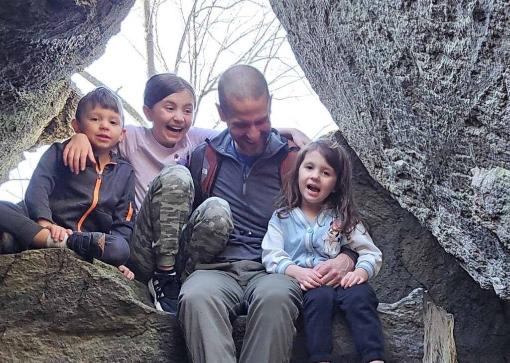 The Bicksler Family - Derek Bicksler with his kids sitting on large boulders and laughing together at whiskey springs hiking area in boiing springs