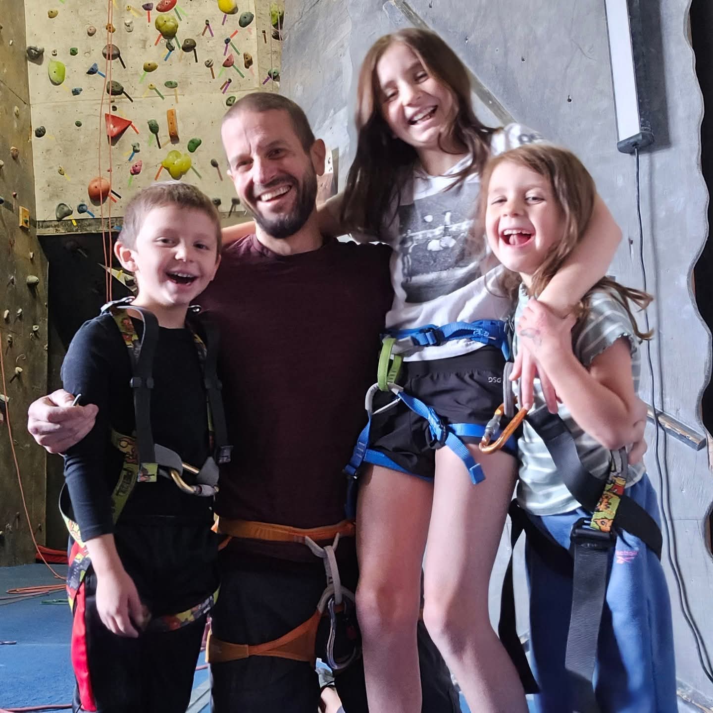 about me image of derek bicksler with his 3 kids at the climbnasium wearing climbing harnesses