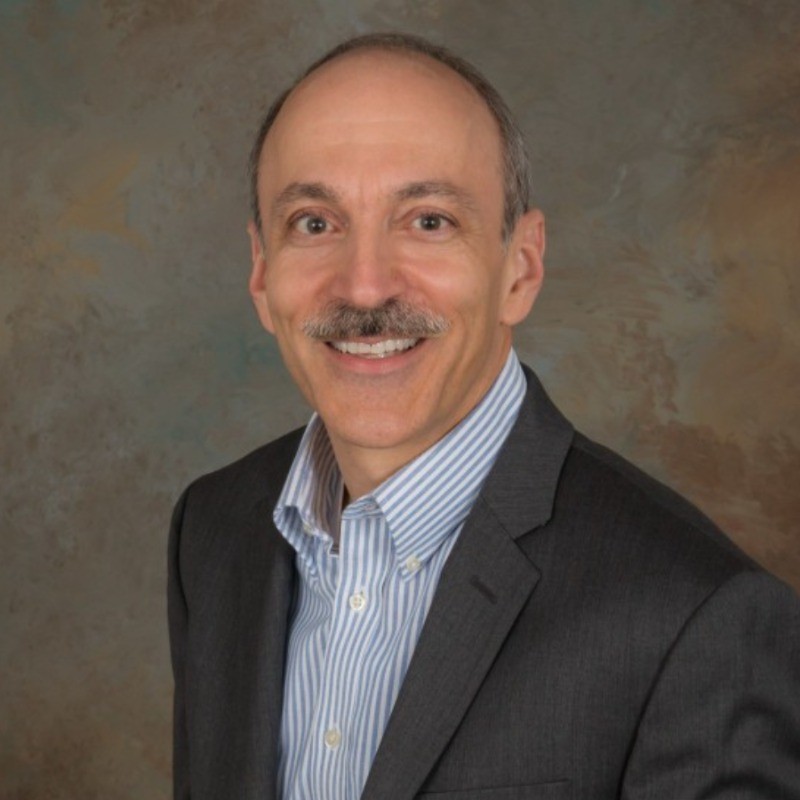 testimonial image of a man with a mustache and suite jacket smiling