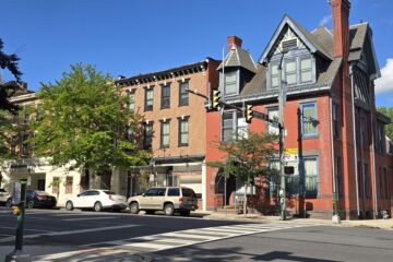 a downtown carlisle streetscape showing multiple buildings on W Pmfret St at the corner of W Pomfret St and S Hanover St - sunny summer day with blue sky - Carlisle Home LIsting Specialist Derek Bicksler