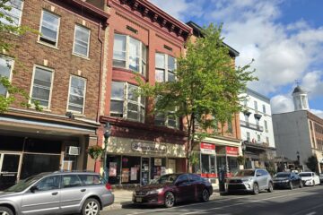 a commercial streetscape in carlisle, pa on s hanover st incuding liberty tax service, state farm insurance office, and comfort suites hotel in downtown carlisle on bright sunny day with blue sky and white fluffy clouds